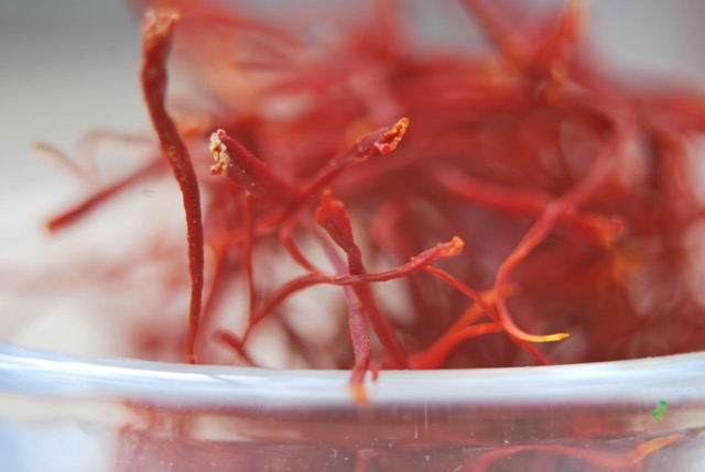 Close-up of premium Iranian saffron threads in a glass container, showcasing the vibrant red strands of Persian saffron, also known as Irani kesar.